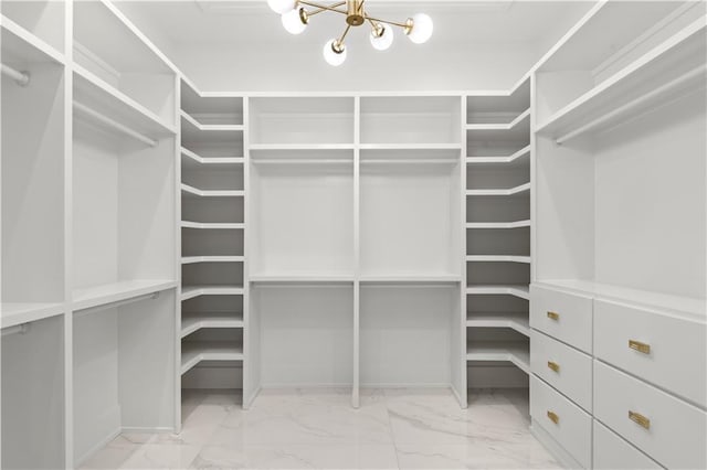 walk in closet featuring marble finish floor and a chandelier