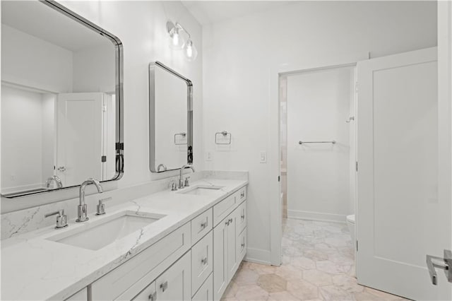 bathroom featuring double vanity, baseboards, and a sink