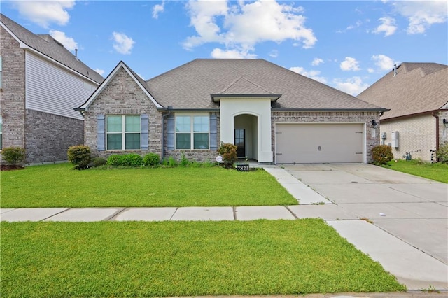 view of front of house with an attached garage, brick siding, a shingled roof, driveway, and a front yard