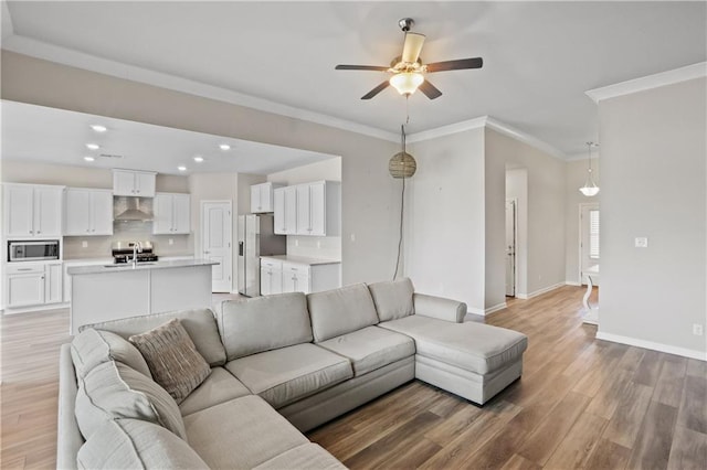 living area with ceiling fan, light wood-style flooring, recessed lighting, baseboards, and ornamental molding