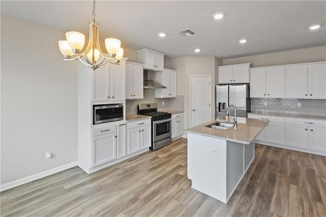 kitchen with stainless steel appliances, visible vents, light wood-style flooring, a sink, and wall chimney exhaust hood