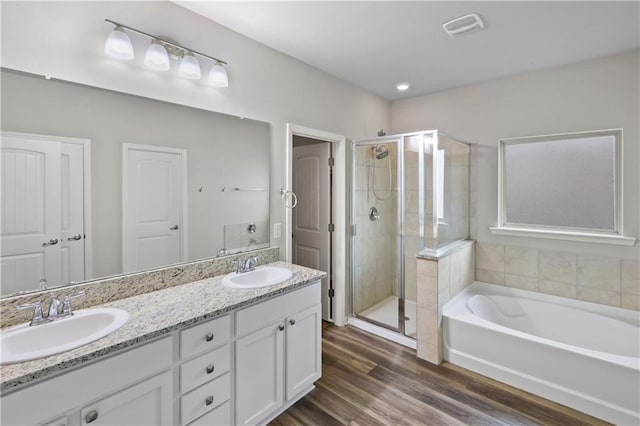 bathroom with visible vents, a sink, a bath, and wood finished floors