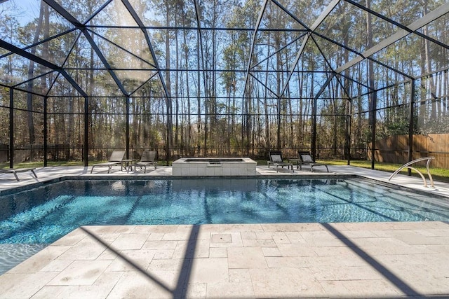 view of pool with a patio area, a pool with connected hot tub, fence, and glass enclosure