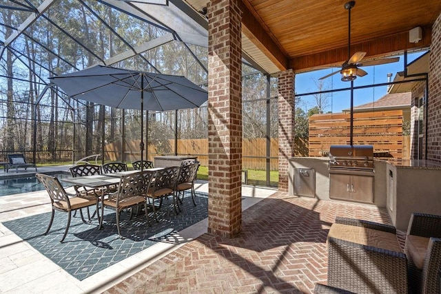 view of patio / terrace featuring area for grilling, glass enclosure, an outdoor kitchen, and fence