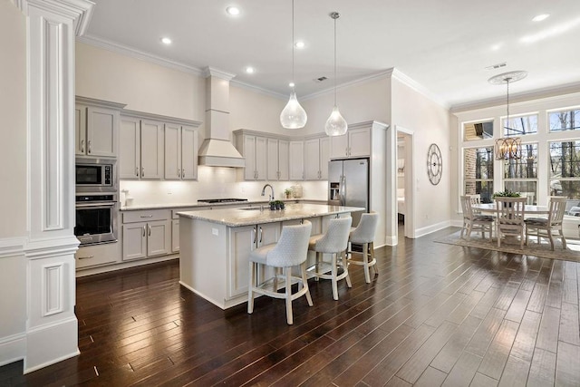 kitchen with stainless steel appliances, dark wood-style flooring, gray cabinets, and an island with sink