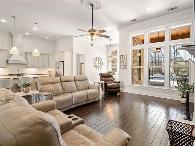 living area with dark wood-style floors, visible vents, ornamental molding, and a ceiling fan