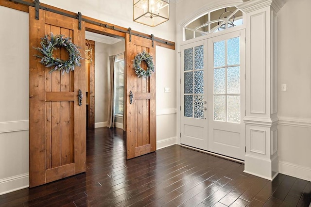 entrance foyer with dark wood-style flooring, baseboards, and a barn door