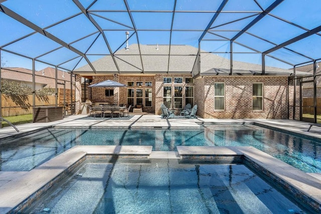 view of swimming pool with glass enclosure, a pool with connected hot tub, and a patio area