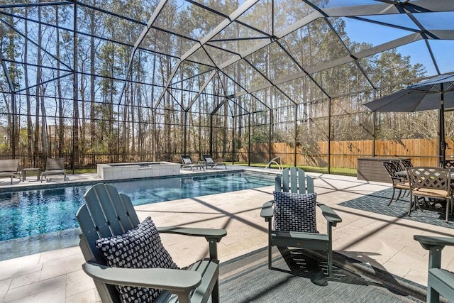 view of swimming pool featuring glass enclosure, a patio area, a fenced backyard, and a pool with connected hot tub