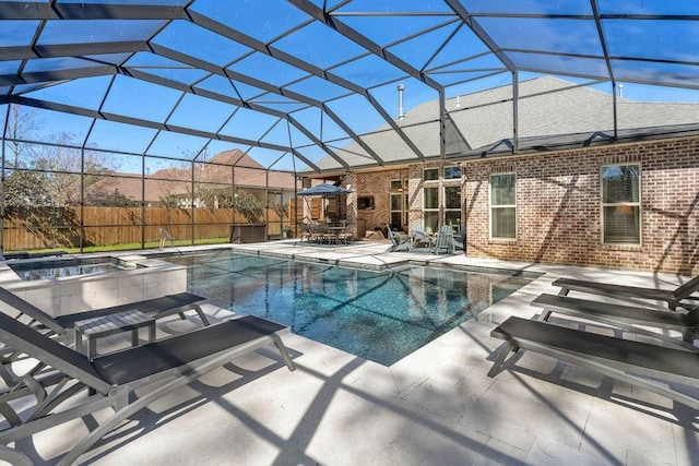 view of swimming pool featuring glass enclosure, a patio area, fence, and a pool with connected hot tub