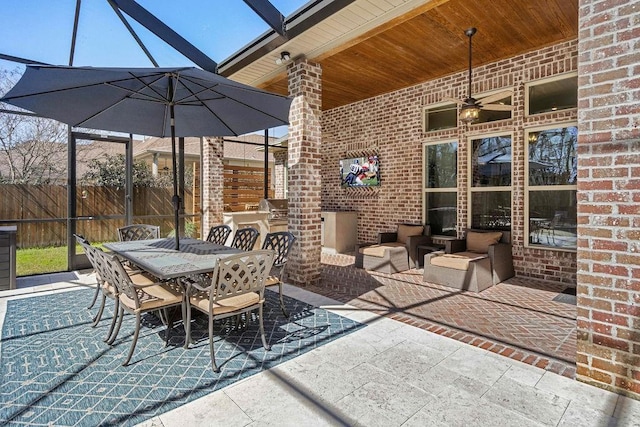 view of patio featuring ceiling fan, outdoor dining area, a lanai, fence, and grilling area