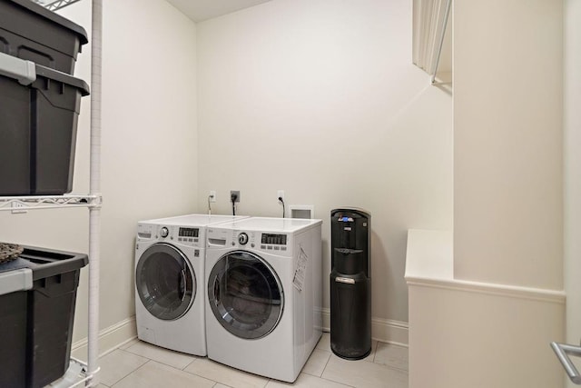 washroom featuring light tile patterned floors, laundry area, separate washer and dryer, and baseboards