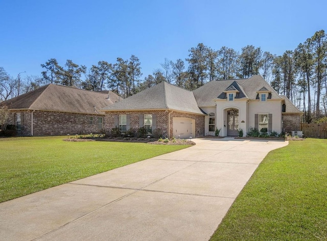 french country style house featuring brick siding, stucco siding, concrete driveway, a garage, and a front lawn