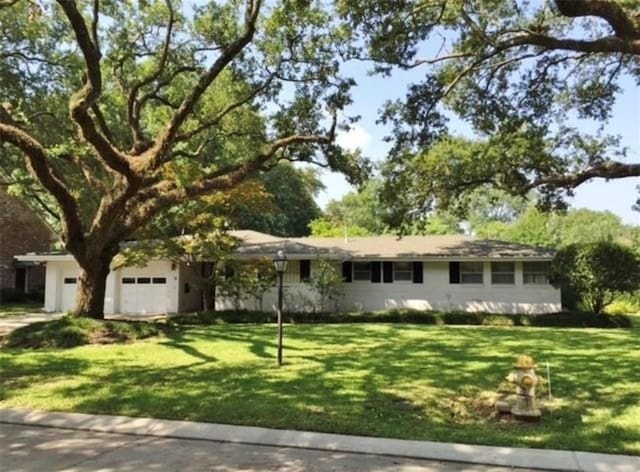 ranch-style home with driveway and a front lawn