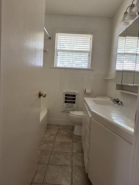 bathroom featuring vanity, heating unit, tile walls, toilet, and tile patterned floors