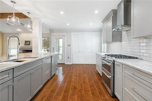 kitchen with wall chimney exhaust hood, double oven range, a sink, and gray cabinetry