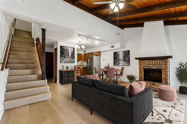 living room featuring light wood-style flooring, stairway, a brick fireplace, and wood ceiling