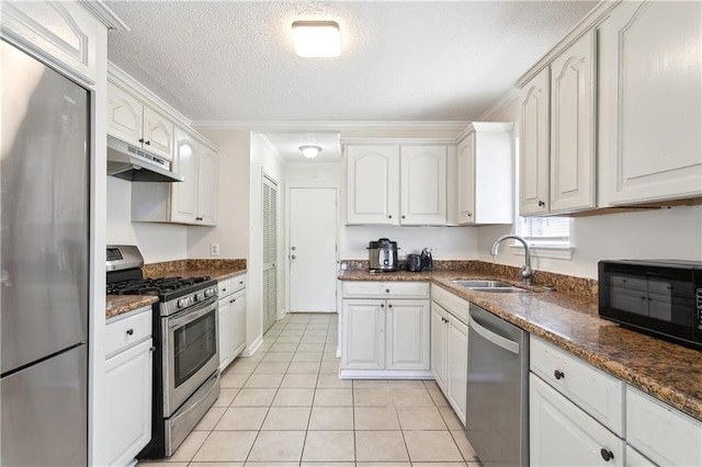 kitchen with stainless steel appliances, light tile patterned flooring, a sink, white cabinetry, and under cabinet range hood