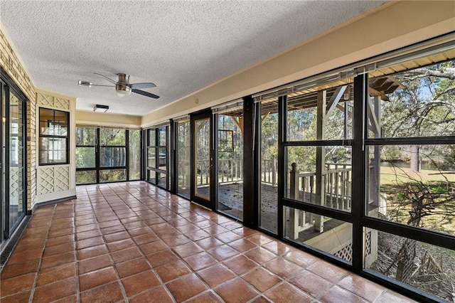 unfurnished sunroom featuring a ceiling fan