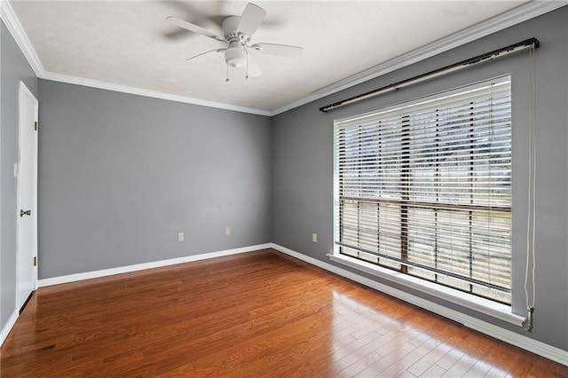 spare room with crown molding, a wealth of natural light, a ceiling fan, wood finished floors, and baseboards