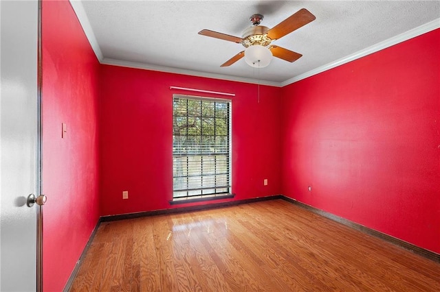 unfurnished room featuring crown molding, a textured ceiling, baseboards, and wood finished floors