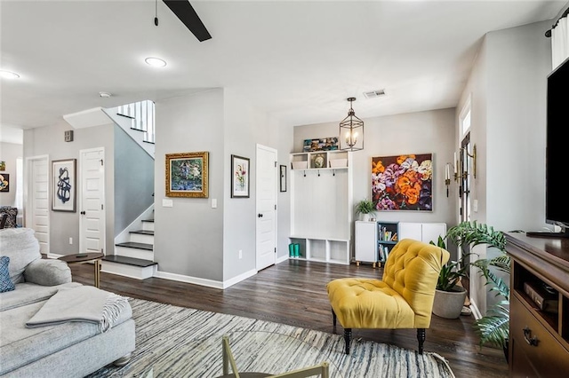 living room with wood finished floors, visible vents, baseboards, and stairs