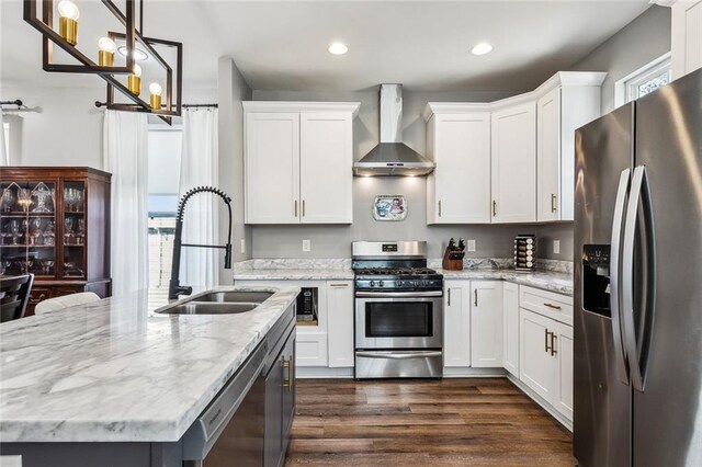 kitchen with dark wood-style floors, stainless steel appliances, white cabinets, a sink, and wall chimney range hood