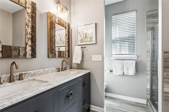 bathroom featuring double vanity, a sink, toilet, and baseboards