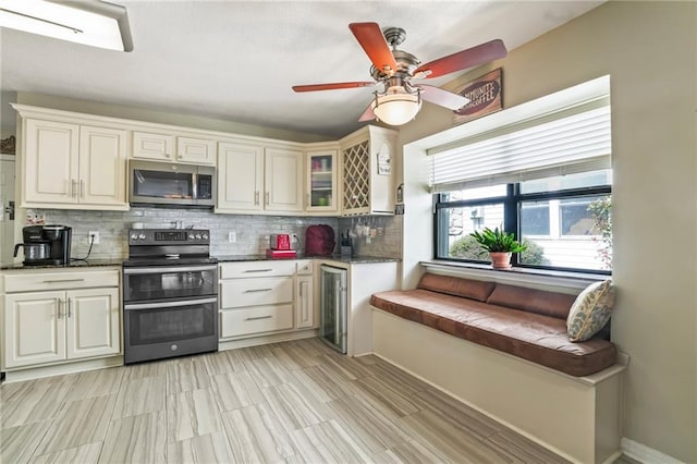 kitchen with dark countertops, wine cooler, glass insert cabinets, appliances with stainless steel finishes, and backsplash