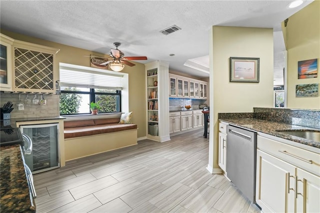 kitchen with wine cooler, visible vents, dishwasher, tasteful backsplash, and glass insert cabinets