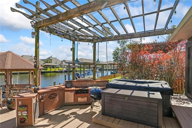 wooden deck featuring an outdoor kitchen, a boat dock, a water view, and a pergola