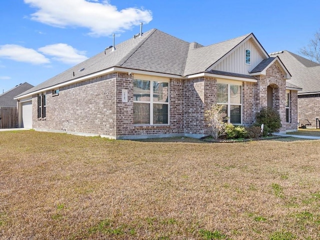 view of front of property with a shingled roof, brick siding, an attached garage, and a front lawn