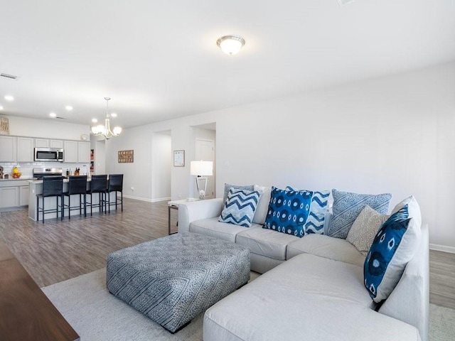 living room with recessed lighting, visible vents, light wood-style floors, a chandelier, and baseboards