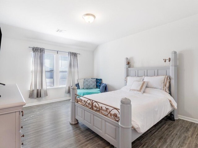 bedroom with visible vents, dark wood finished floors, and baseboards