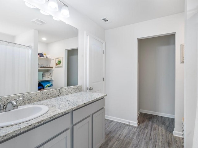 bathroom featuring visible vents, vanity, baseboards, and wood finished floors