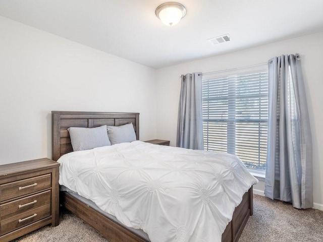 bedroom featuring visible vents, light carpet, and multiple windows