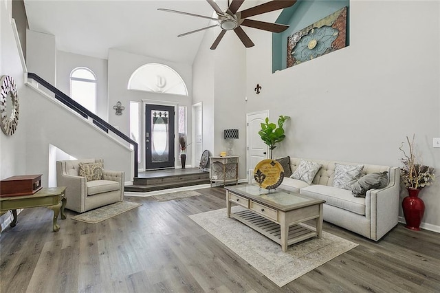 living room with ceiling fan, a high ceiling, stairway, and wood finished floors