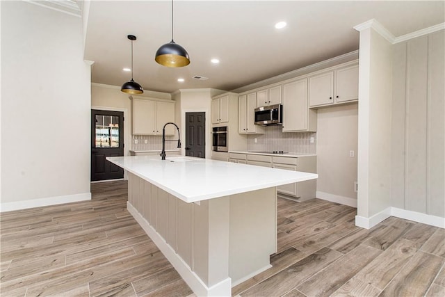 kitchen with ornamental molding, appliances with stainless steel finishes, a sink, and light wood-style floors