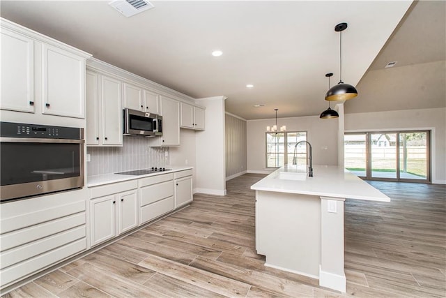 kitchen with light wood-style flooring, a sink, visible vents, appliances with stainless steel finishes, and backsplash