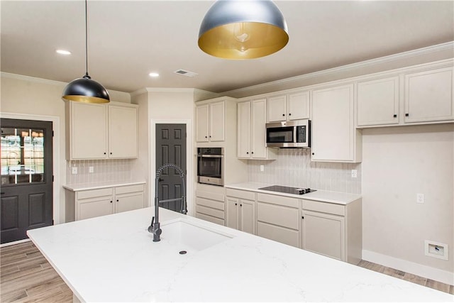 kitchen featuring light wood finished floors, visible vents, ornamental molding, stainless steel appliances, and a sink