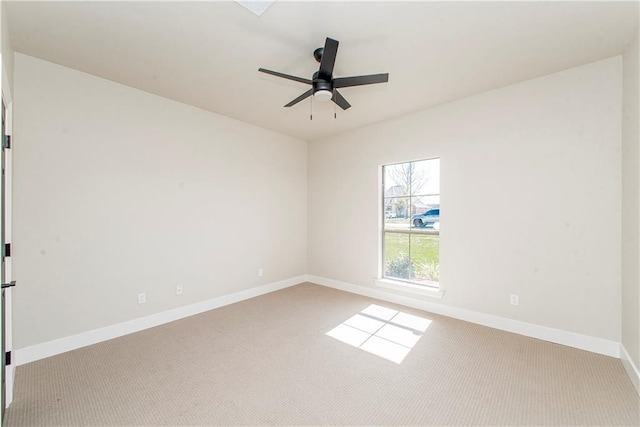 carpeted empty room featuring a ceiling fan and baseboards