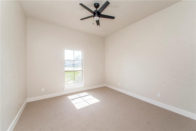 carpeted spare room with a ceiling fan and baseboards