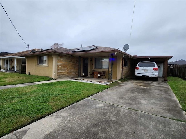 single story home with a front yard, brick siding, driveway, and solar panels