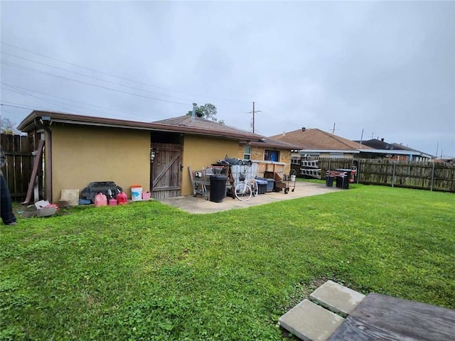 back of property featuring a patio, a lawn, fence, and stucco siding