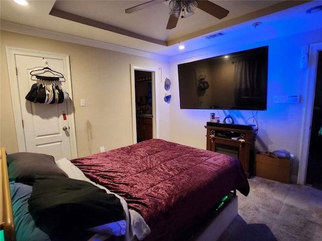 bedroom featuring a tray ceiling, crown molding, visible vents, carpet flooring, and ceiling fan