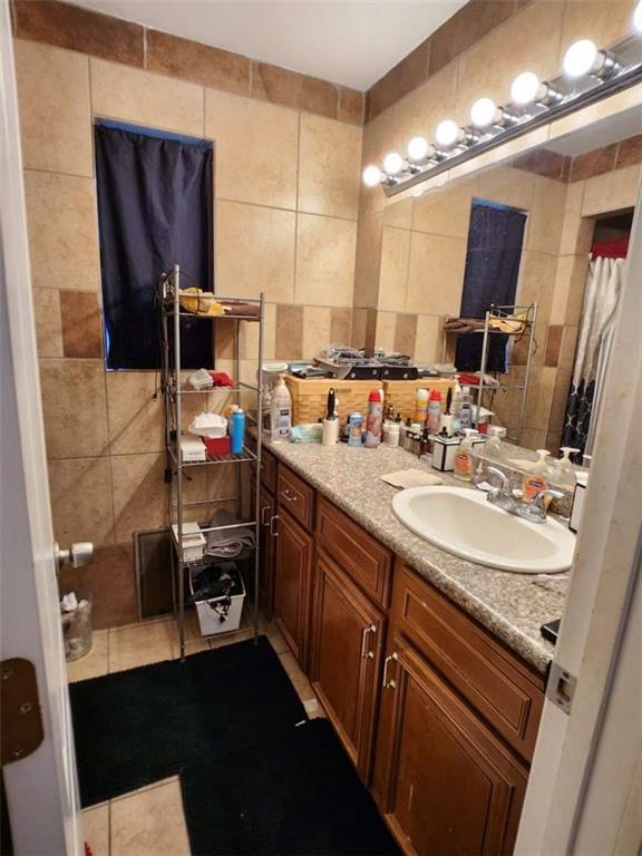 bathroom featuring decorative backsplash, tile patterned flooring, tile walls, and vanity