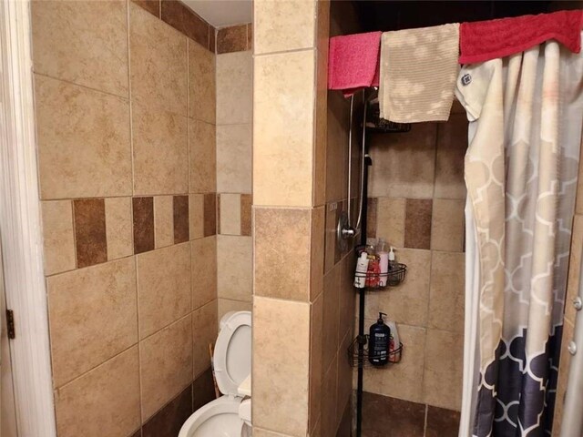 bathroom featuring curtained shower, toilet, and tile walls