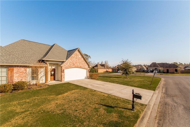 view of front facade with driveway, roof with shingles, an attached garage, a front yard, and brick siding