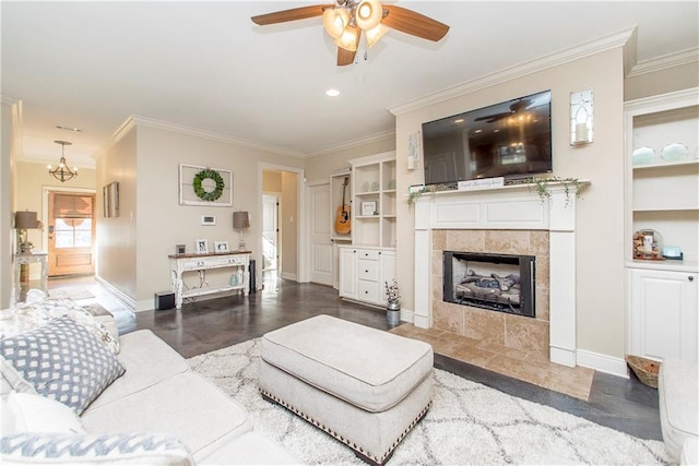 living area featuring built in shelves, a tile fireplace, crown molding, and baseboards