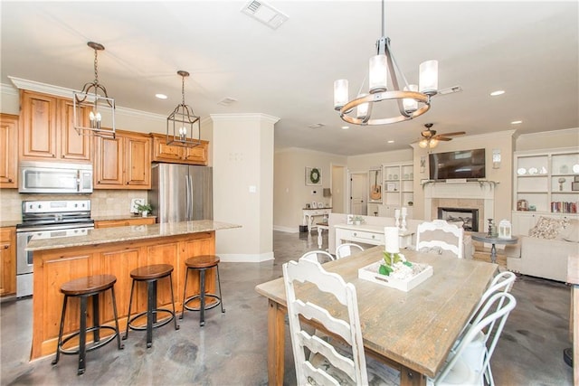 dining space with concrete flooring, visible vents, baseboards, ornamental molding, and a tiled fireplace